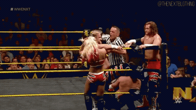 A Group Of Wrestlers Are Fighting In A Wrestling Ring With A Referee Watching . GIF