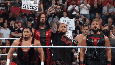 A Group Of Wrestlers Are Holding Up A Sign That Says Sucks GIF