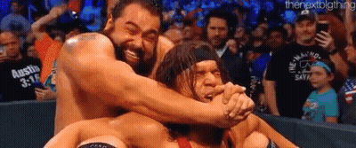 A Group Of Wrestlers Are Hugging Each Other On A Wrestling Ring In Front Of A Crowd . GIF