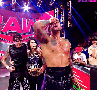 A Group Of Wrestlers Are Posing For A Picture With The Word Raw In The Background GIF
