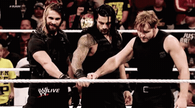 A Group Of Wrestlers Are Standing In A Ring Holding Hands . GIF