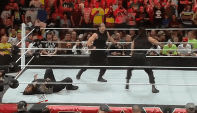 A Group Of Wrestlers Are Standing In A Ring With A Crowd Watching . GIF