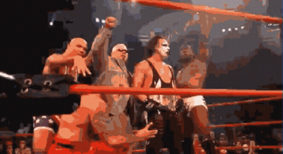 A Group Of Wrestlers Are Standing In A Ring With A Sign That Says G On It GIF