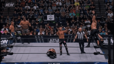 A Group Of Wrestlers Are Standing In A Ring With A Sign That Says Hey On It GIF