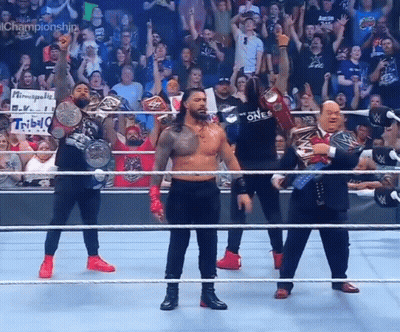 A Group Of Wrestlers Are Standing In A Ring With Their Championship Belts GIF