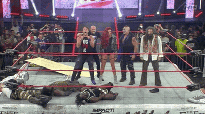 A Group Of Wrestlers Are Standing In A Wrestling Ring And One Of Them Is Wearing A Black Shirt With The Letter K On It GIF
