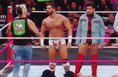 A Group Of Wrestlers Are Standing In A Wrestling Ring Holding Hands . GIF