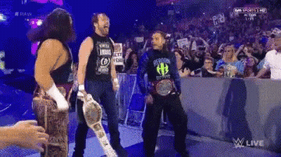 A Group Of Wrestlers Are Standing In Front Of A Crowd And One Of Them Is Wearing A Shirt With The Letter H On It GIF
