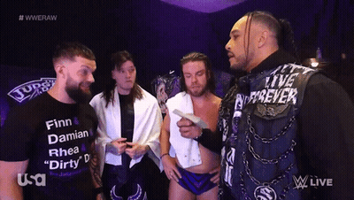A Group Of Wrestlers Are Standing In Front Of A Screen That Says Wweraw GIF