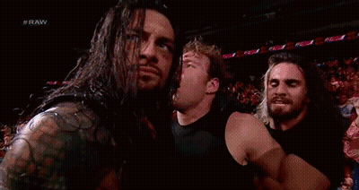 A Group Of Wrestlers Are Standing Next To Each Other In A Stadium . GIF