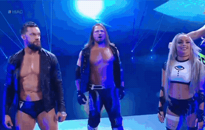 A Group Of Wrestlers Are Standing Next To Each Other On A Stage In Front Of A Blue Background . GIF