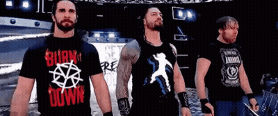 A Group Of Wrestlers Are Standing Next To Each Other On A Stage In Front Of A Crowd . GIF