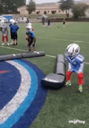 A Group Of Young Boys Are Playing Football On A Field GIF