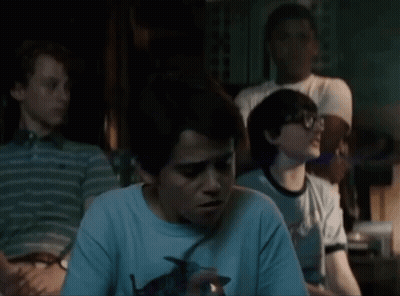 A Group Of Young Boys Are Sitting In A Dark Room And One Of Them Is Holding A Lighter . GIF