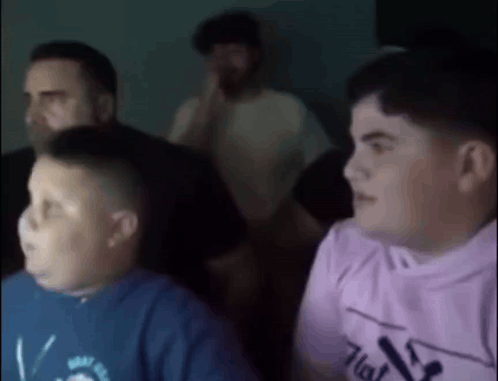 A Group Of Young Boys Are Sitting In Front Of A Screen . GIF