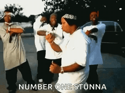 A Group Of Young Men Are Dancing In A Parking Lot And One Of Them Is Wearing A Bandana . GIF