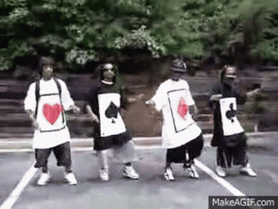 A Group Of Young Men Are Dancing In A Parking Lot While Wearing Playing Cards Shirts . GIF