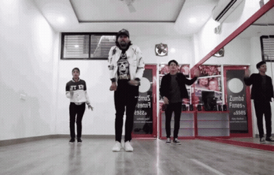 A Group Of Young Men Are Dancing In Front Of A Sign That Says Zumba Fines GIF