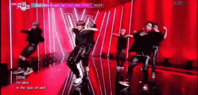 A Group Of Young Men Are Dancing On A Stage In Front Of A Red Curtain . GIF