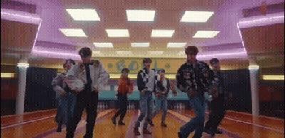 A Group Of Young Men Are Dancing Together In A Bowling Alley . GIF