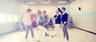 A Group Of Young Men Are Dancing Together In A Room In A School . GIF