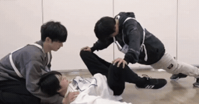 A Group Of Young Men Are Doing Exercises On The Floor . GIF