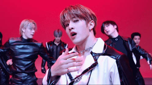 A Group Of Young Men Are Performing On A Stage With A Red Background GIF
