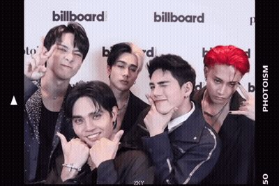 A Group Of Young Men Are Posing For A Picture In Front Of A Billboard Sign GIF