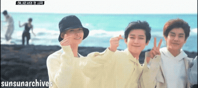 A Group Of Young Men Are Posing For A Picture On A Beach With Sunsunarchives Written On The Bottom Right GIF