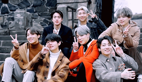 A Group Of Young Men Are Posing For A Picture While Giving Peace Signs GIF