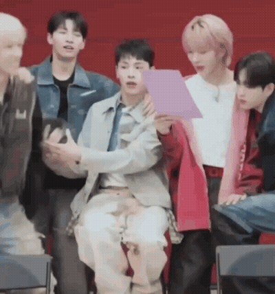 A Group Of Young Men Are Sitting In Chairs And Talking To Each Other . GIF
