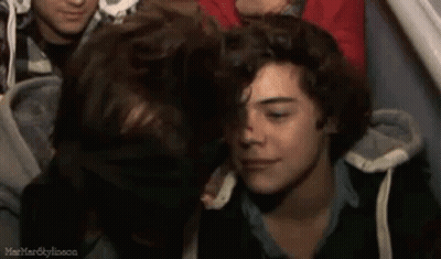 A Group Of Young Men Are Sitting Next To Each Other In A Crowd . GIF