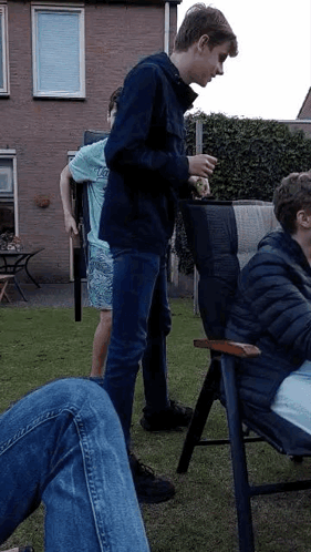 A Group Of Young Men Are Standing And Sitting In A Yard . GIF