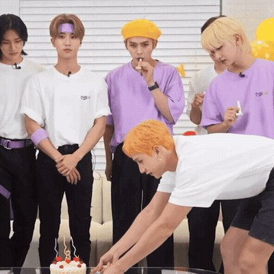 A Group Of Young Men Are Standing Around A Cake With Candles GIF