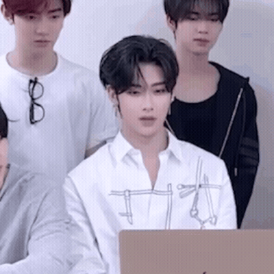 A Group Of Young Men Are Standing Around A Laptop Computer . One Of The Men Is Wearing Glasses . GIF