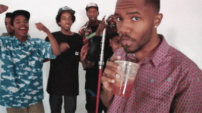 A Group Of Young Men Are Standing Around A Man Drinking A Drink Through A Straw GIF