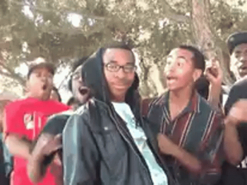 A Group Of Young Men Are Standing In A Park . GIF