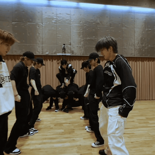 A Group Of Young Men Are Standing In A Room And One Of Them Is Wearing A Shirt That Says " Supreme " On It GIF