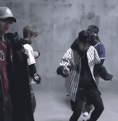 A Group Of Young Men Are Standing In A Room . GIF