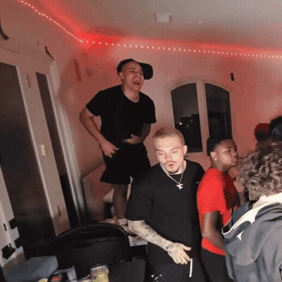 A Group Of Young Men Are Standing In A Room With A Red Light On The Ceiling GIF