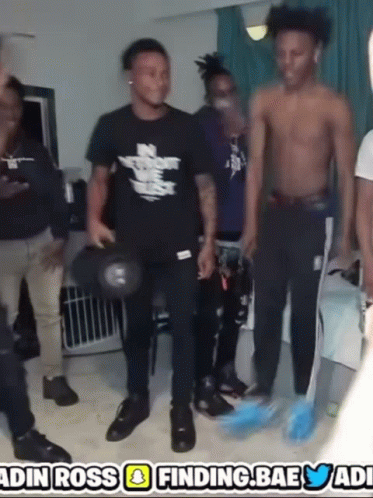 A Group Of Young Men Are Standing In A Room With A Sign That Says ' Finding Bae ' GIF