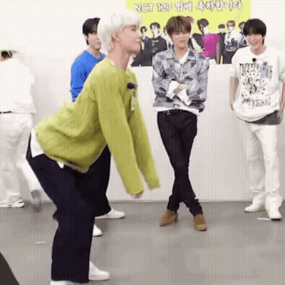 A Group Of Young Men Are Standing In A Room . GIF