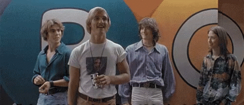 A Group Of Young Men Are Standing In Front Of A Colorful Wall With The Letter P On It GIF