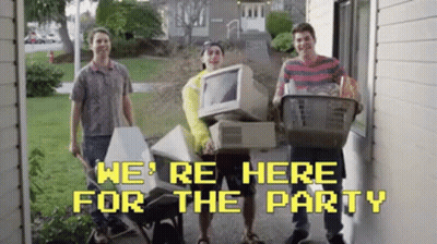 A Group Of Young Men Are Standing In Front Of A House Holding A Computer And A Basket Of Groceries . GIF