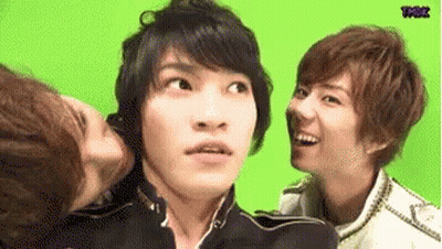 A Group Of Young Men Are Standing Next To Each Other And One Of Them Is Kissing Another Man On The Cheek . GIF