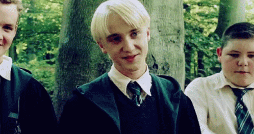 A Group Of Young Men Are Standing Next To Each Other In A Forest . One Of The Boys Is Wearing A Green Tie . GIF