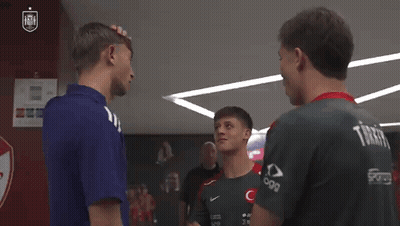 A Group Of Young Men Are Standing Next To Each Other In A Locker Room Talking To Each Other . GIF