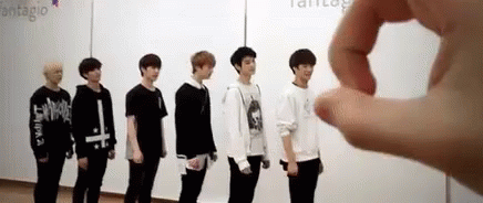 A Group Of Young Men Are Standing Next To Each Other In A Row In Front Of A White Wall . GIF