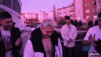 A Group Of Young Men Are Standing Next To Each Other On A City Street . GIF