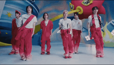 A Group Of Young Men Are Standing Next To Each Other Wearing Pink Overalls And White Shirts . GIF